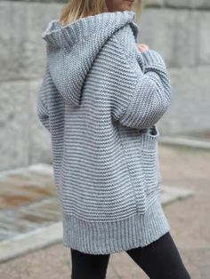 a woman in grey sweater and black leggings walking down the street with her hand on her hip