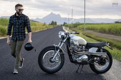 a man walking next to a motorcycle on the road