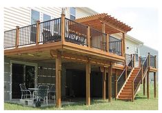 a house with a deck and stairs leading to the upper level balcony, next to a patio