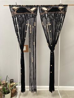 two black curtains with beaded fringes and pearls on them in front of a white wall