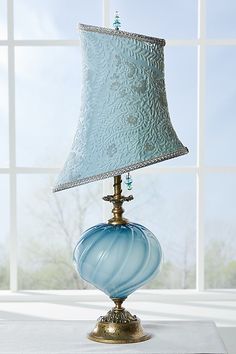 a blue lamp sitting on top of a table next to a window