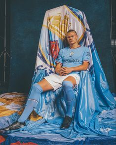 a man sitting on top of a blue tarp next to a soccer goalie