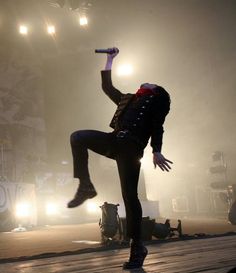 a man is jumping in the air with his legs up on stage and lights behind him