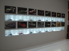 there are many cars displayed on the wall in this room with white walls and flooring