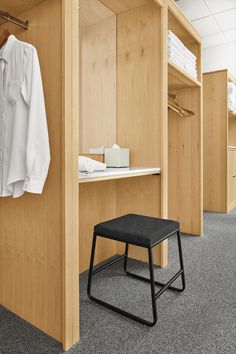 a room with some clothes hanging on the wall and a stool in front of it