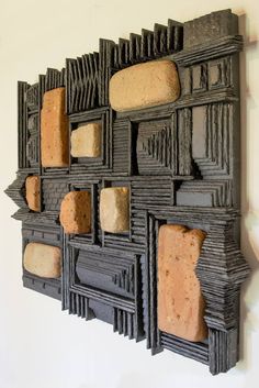 a wall sculpture made out of wood and stone blocks with holes in the middle, on a white wall