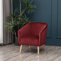 a red chair sitting next to a potted plant on top of a hard wood floor