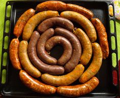 several sausages are arranged in a spiral on a black tray