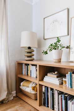 a bookshelf filled with lots of books next to a lamp and pictures on the wall