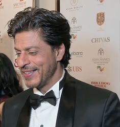 a man in a tuxedo smiles at the camera