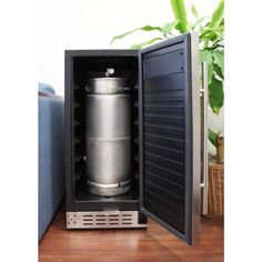 an open mini fridge on a table with a plant in the corner and a potted plant next to it