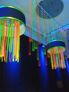 colorful lights hanging from the ceiling in a room with black curtains and drapes on the walls