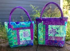 two purple and green bags sitting on top of a rock