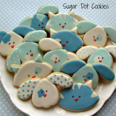 a white plate topped with lots of blue and white decorated sugar cookies on top of a table