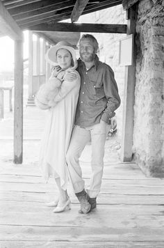 black and white photograph of man and woman standing under an awning holding each other