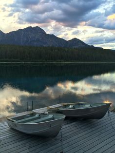 two canoes tied up on a dock with mountains in the background