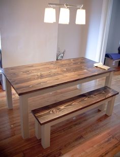 a wooden table and bench in a room with hard wood flooring on the ground