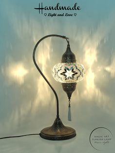 an ornate lamp is lit up against a blue background with the words handmade light and love written below it