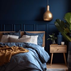 a bed with blue sheets and pillows in a bedroom next to a plant on the nightstand