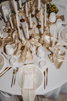 the table is set with white and gold plates, silver napkins, and candles