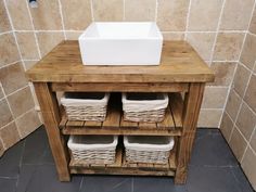 a wooden cabinet with baskets on top and a sink in the middle, next to a tiled wall