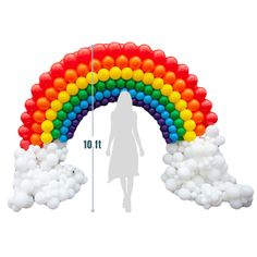 a woman standing in front of a rainbow shaped balloon arch with white clouds surrounding it