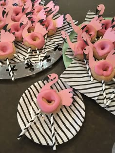 donuts with pink frosting and sprinkles on top of black and white paper plates