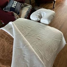 an unmade bed with pillows and blankets on it in a living room next to a couch