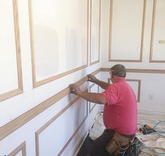 a man is working on the wall in his house with wood trimmings and paint