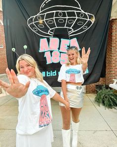 two girls in costumes standing next to a sign