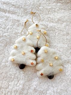 two white christmas trees with gold stars hanging from them on a white bed coverlet