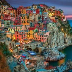 the colorful village is perched on top of a cliff by the ocean at night time