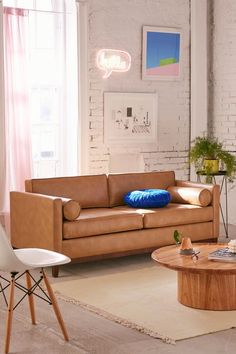 a living room with two couches and a coffee table in front of a brick wall