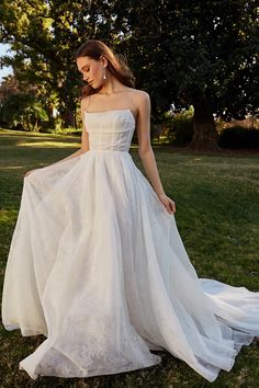 a woman in a white dress standing on grass