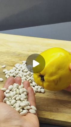 a person is cutting up some beans on a wooden board with a yellow tomato in the background