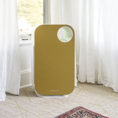 an air purifier sitting on top of a rug next to a window