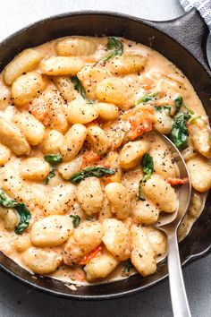 a skillet filled with pasta and spinach