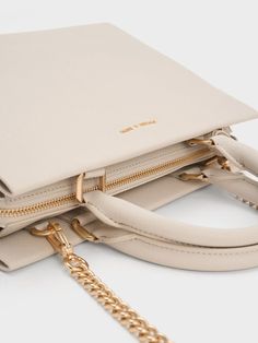 This product is made with at least 20% sustainable materials by weight. CHARLES & KEITH uses recycled, degradable, organic, and water-based materials in our eco-conscious collection. You can never go wrong with a classy carrier in a versatile shade, and this iteration of the Mirabelle bag is exactly that. The creamy ivory finish and structured silhouette makes clean lines the focal point, with a luxurious gold-accent bag charm to add shine. Maximising functionality, the roomy interior comes with inner compartments to keep all your essentials organised and secure. Carry this nifty bag with ease by its top handles, or attach the accompanying strap to turn it into a posh shoulder bag. Neutral Handbag, Structured Top, Charles Keith, Cute Bags, Handle Bag, Gold Accents, Top Handle, Top Handle Bag, Handles