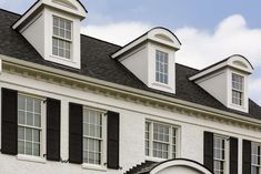 a white house with black shutters and a clock