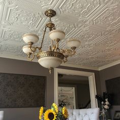 a chandelier hanging from the ceiling with sunflowers in front of it