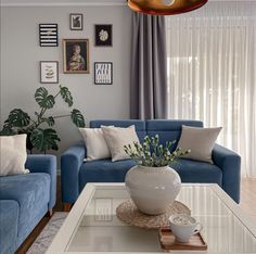 a living room with blue couches and pictures on the wall above them, along with a coffee table