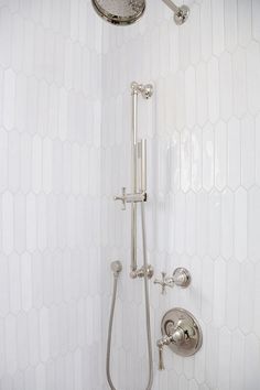 the shower head and handset are connected to the faucet in this white tiled bathroom