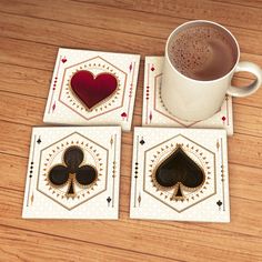 four playing cards and a cup of coffee on a wooden table with wood flooring