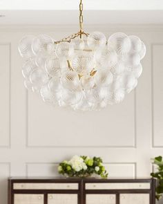 a chandelier hanging from the ceiling in a room with white walls and furniture