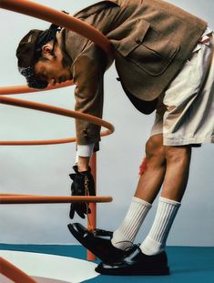 a man in shorts and socks leaning on a metal rail with his head down while wearing black shoes