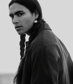 a black and white photo of a woman with braids in her hair looking at the camera