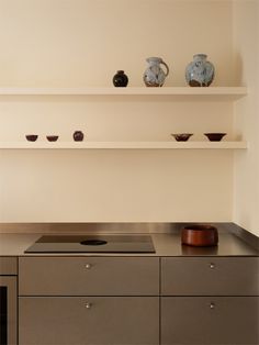 a kitchen counter with some bowls on top of it and two shelves above the stove