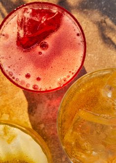 an overhead view of two glasses filled with liquid and ice cubes on the ground