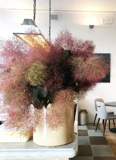 a vase filled with flowers sitting on top of a counter next to a dining room table