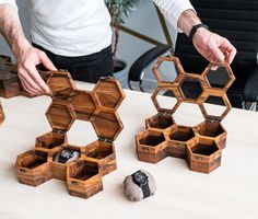 a man standing next to wooden boxes on top of a table with scissors in them